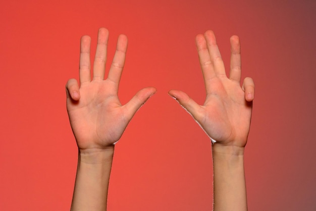 The human hand shows four fingers isolated on a red background