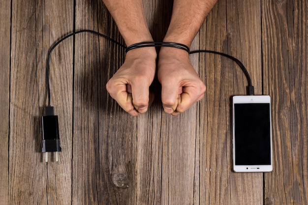 Human hands are associated with charging of the phone as a symbol of dependence on technology and workaholism