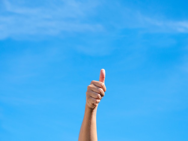 Human hands with thumb up in the clear blue sky Gesture and body parts concept OK good great