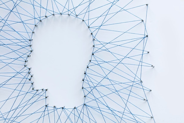 Human head shape made from a large grid of pins connected with string Communication technology and mental health concept