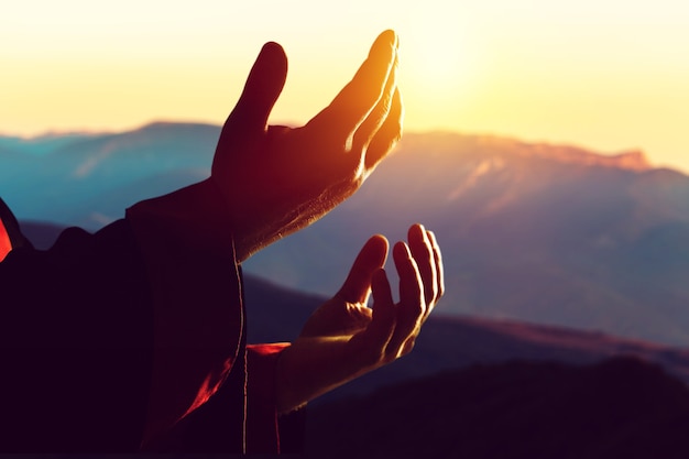 Human male hand praying outdoor