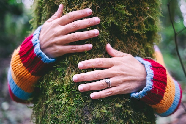 Human people hands hug embrace with love a green trunk with musk in the wild nature Concept of love and protection nature outdoors Leisure activity in the park Environment lifestyle help and save