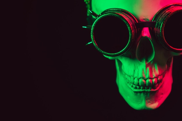 Human skull in steampunk glasses with colored neon light