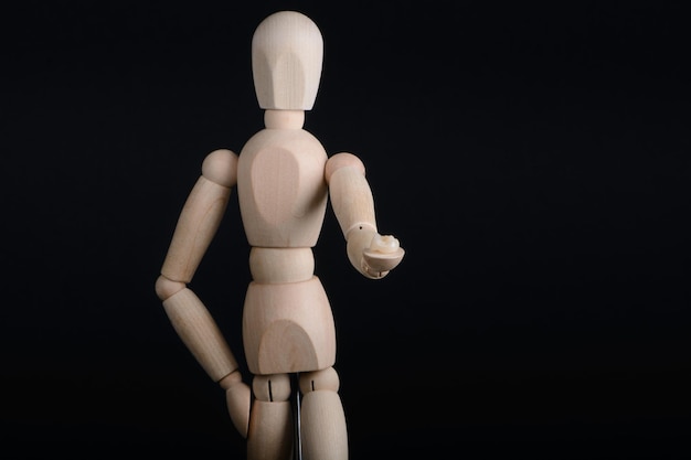 Human wooden figure holds in hands a zirconia bridge with glazour on a black background