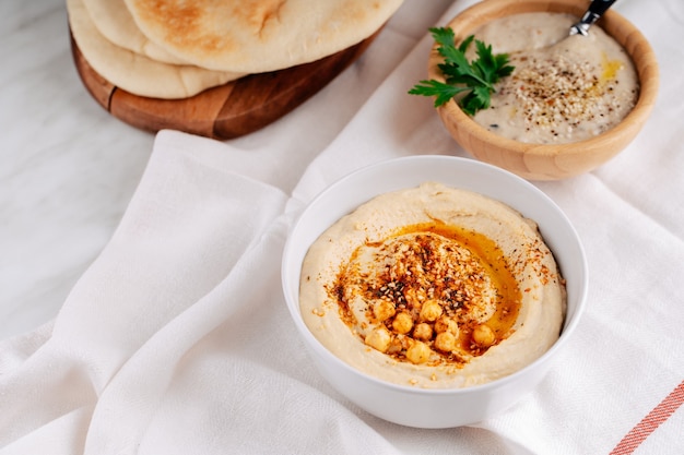 Hummus and baba ghanoush in a bowl and pita bread on a light background.