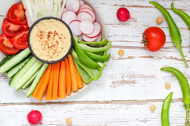 Hummus in bowl, vegetables sticks, chickpeas, olives