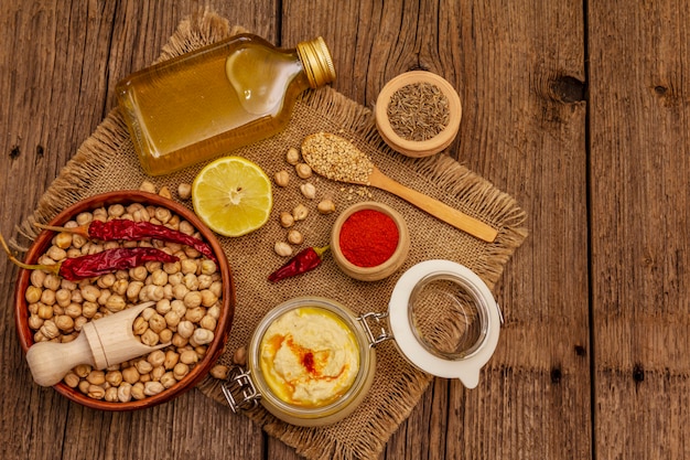 Hummus on old wooden table. Dry chickpea, olive oil, lemon, cumin and chili pepper