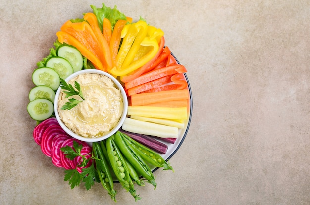 Hummus platter with assorted vegetable snacks. Healthy vegan and vegetarian food. Top view, flat lay, copy space.