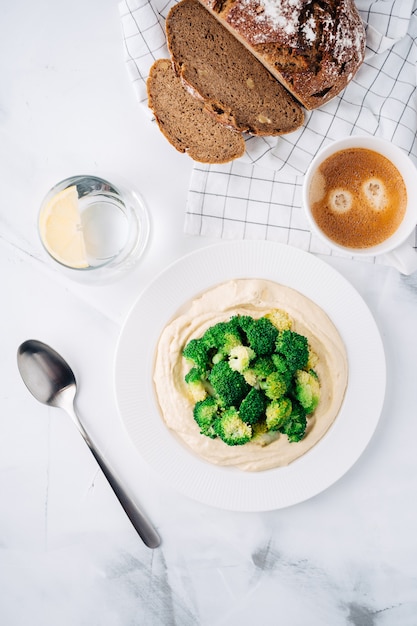 Hummus with broccoli, bread and coffee with water. Breakfast. Middle Eastern dish. Top view