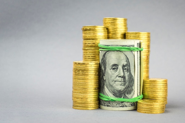 Hundred dollar banknote with gold coins on a gray background financial concept