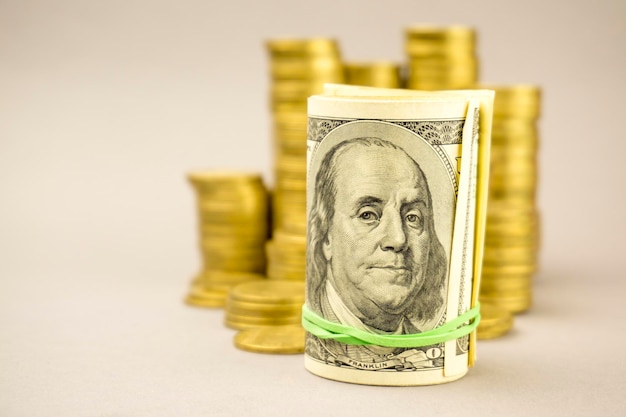 Hundred dollar banknote with gold coins on a gray background financial concept