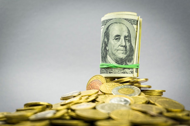 Hundred dollar banknote with gold coins on a gray background financial concept