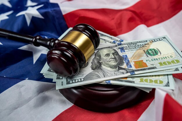 Hundred dollar bills and a judge's gavel are placed on an American flag