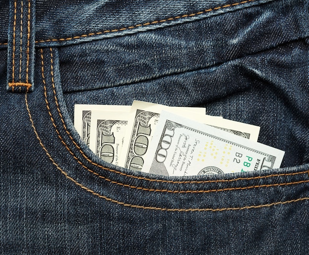 hundred United States dollar bills in the pocket of jeans