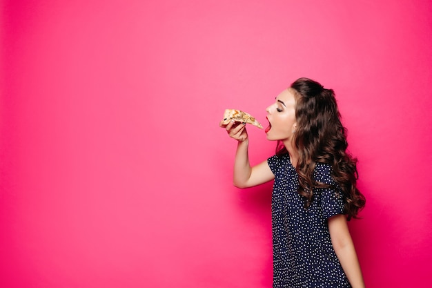 Hungry girl with opened mouth eating big hamburger.