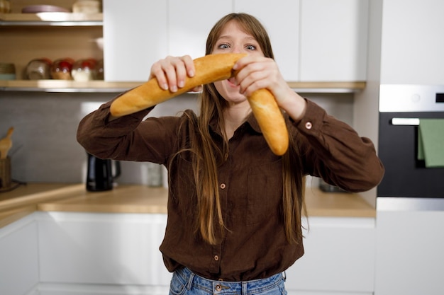 Hungry woman breaking fresh baguette in the kitchen