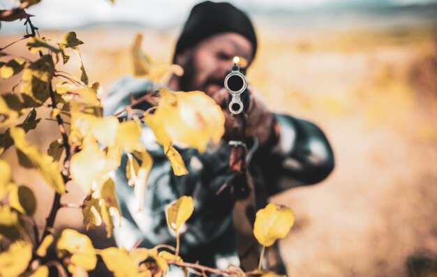 Hunter aiming rifle in forest Autumn hunting season Hunter with shotgun gun on hunt Track down