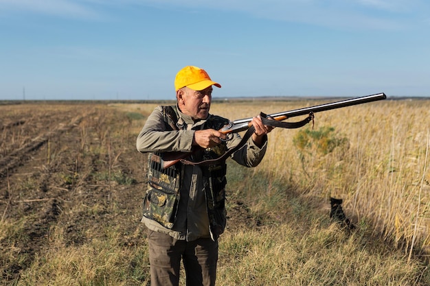 Hunter aiming with rifle while standing against sky