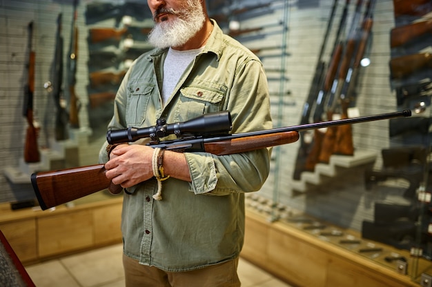 Hunter holds rifle with optical sight in gun store