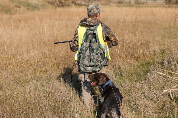 Hunter man in camouflage with a gun during the hunt in search of wild birds or game