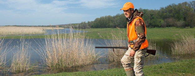 Hunter man in camouflage with a gun during the hunt in search of wild birds or game