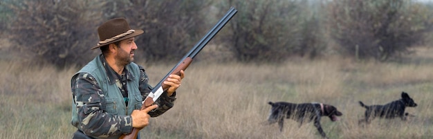 Hunter man in camouflage with a gun during the hunt in search of wild birds or game