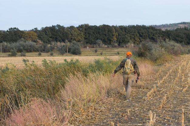 Hunter man in camouflage with a gun during the hunt in search of wild birds or game.