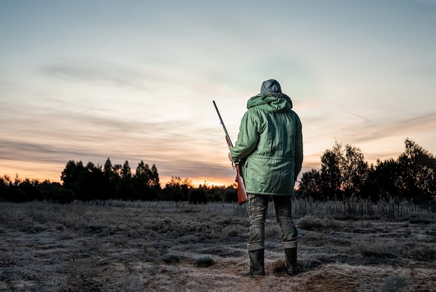 Hunter man in camouflage with a gun during the hunt