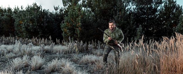 Hunter man in camouflage with a gun during the hunt