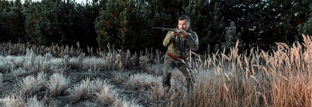 Hunter man in camouflage with a gun during the hunt