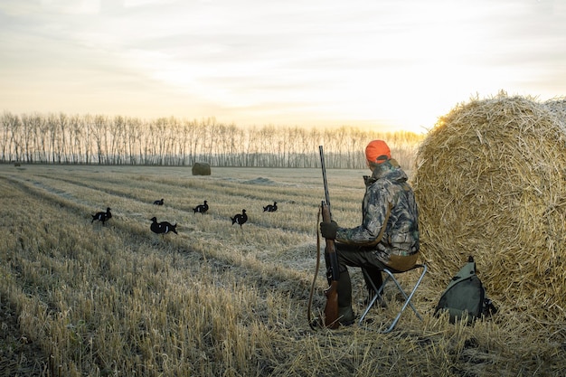 Hunter man Hunting period autumn season Male with a gun in an autumn field at sunrise