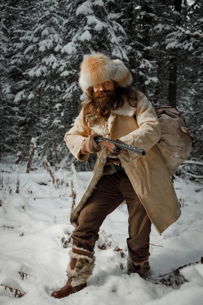 Hunter in vintage clothes with gun sneaks through forest