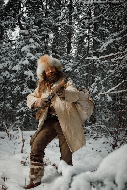 Hunter in vintage clothes with gun sneaks through forest