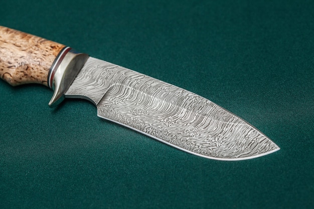 Hunting damascus steel knife handmade on a green fabric