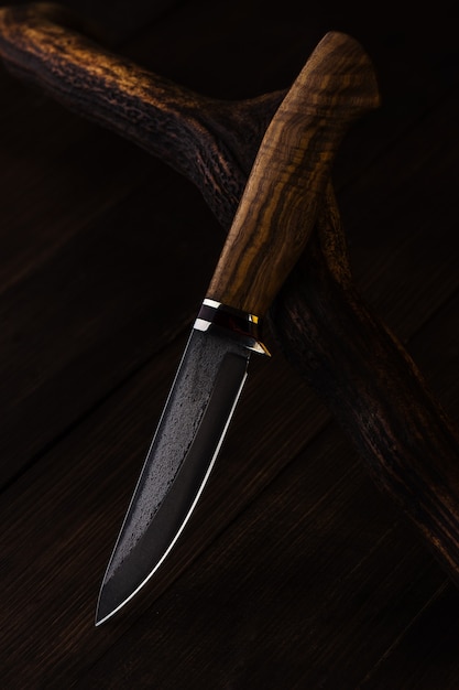 Hunting knife made of damascus steel on wooden background