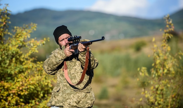 Hunting masculine hobby concept Man brutal gamekeeper nature background Hunter hold rifle Bearded hunter spend leisure hunting Focus and concentration of experienced hunter Regulation of hunting