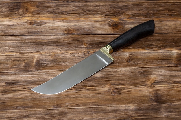 Hunting steel knife on brown wooden table