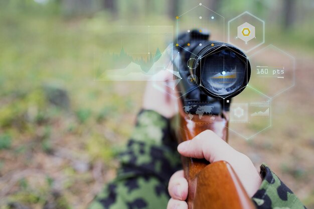 hunting, war, army, technology and people concept - close up of young soldier or sniper hands holding gun with virtual screen projection and aiming in forest