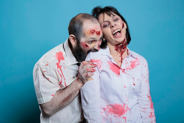 Husband biting wife doing professional photoshoot dressed as zombies