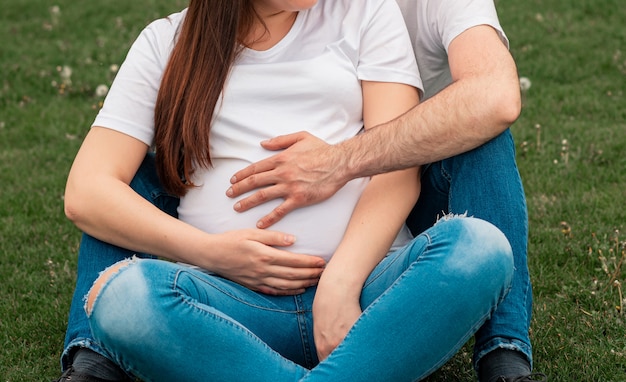 Husband hands on pregnant woman belly outside