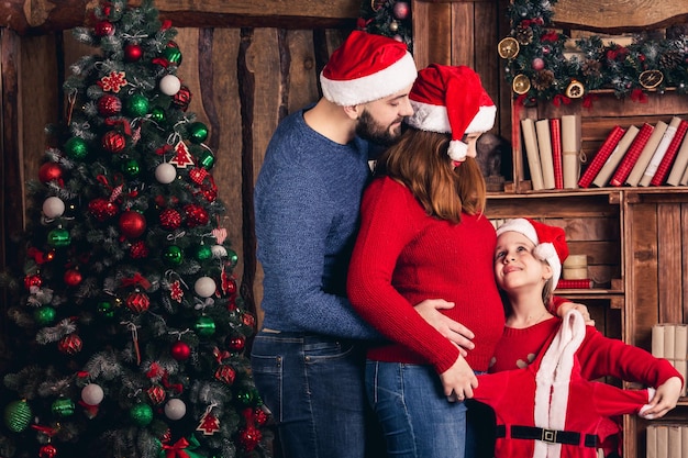 Husband pregnant wife and daughter hold a Christmas costume for the baby