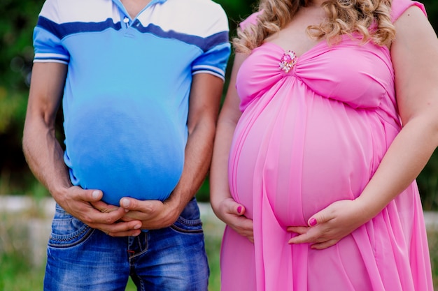 Husband and pregnant wife keep both with their big stomaches