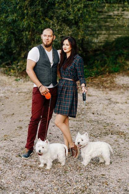 Husband with a beautiful wife walking their white dogs in the park