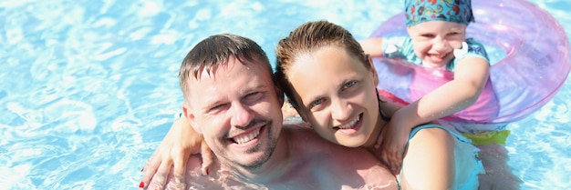 Husband with wife and child swim together in the pool