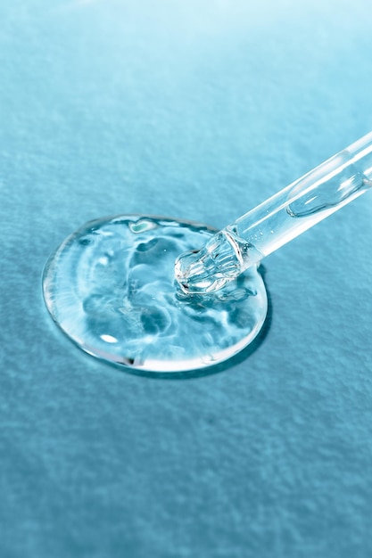 Hyaluronic transparent gel with a glass dropper on a blue background closeup front view