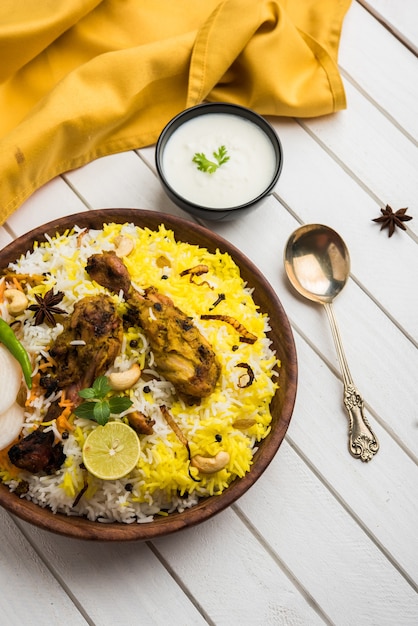 Hyderabadi chicken or dum biryani, served in a Kadhai or bowl with yogurt dip . selective focus