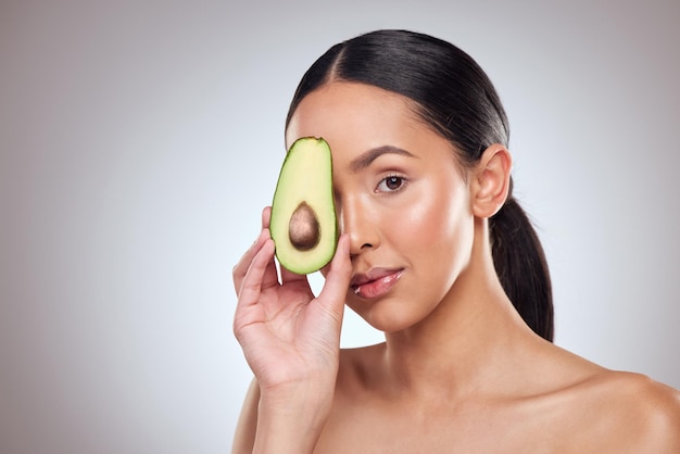 Hydrate and moisturise your skin with avocado Studio portrait of a beautiful young woman posing with an avocado against a grey background