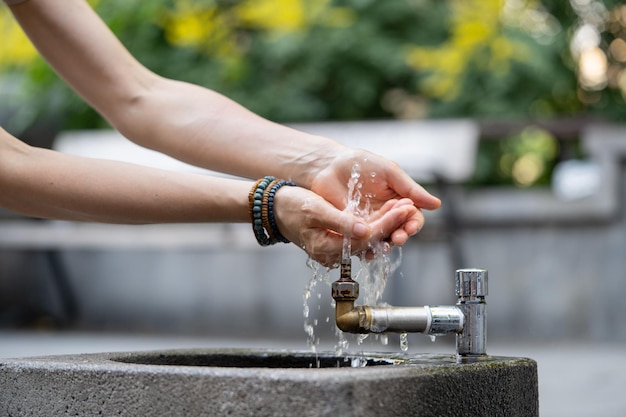 Hydration and aqua balance regulation for health hands with water pouring from tap in street