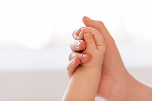 I am always near. Close-up of mother hand holding hand of her little baby