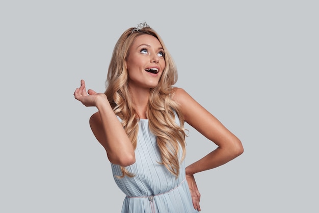 I am fabulous and I know it. Attractive young woman gesturing and looking up while standing against grey background